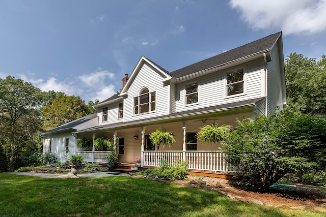 view of front of house with a porch, a front yard, and a chimney