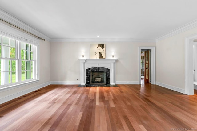 unfurnished living room featuring hardwood / wood-style floors, ornamental molding, and a premium fireplace