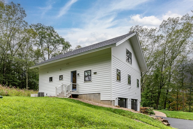 view of front of house with central AC, a front yard, and a garage