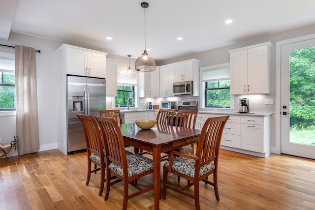 dining space with a wealth of natural light, light wood-type flooring, and sink