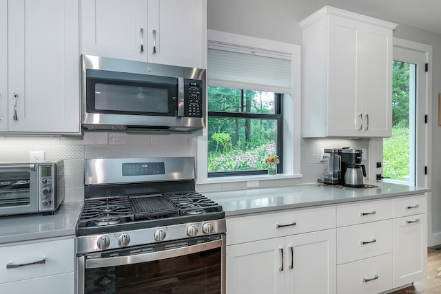 kitchen with white cabinets, appliances with stainless steel finishes, decorative backsplash, and a wealth of natural light