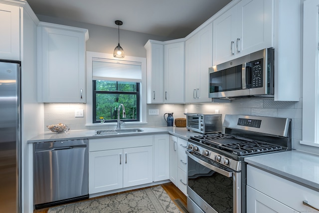 kitchen with decorative backsplash, white cabinetry, appliances with stainless steel finishes, and sink