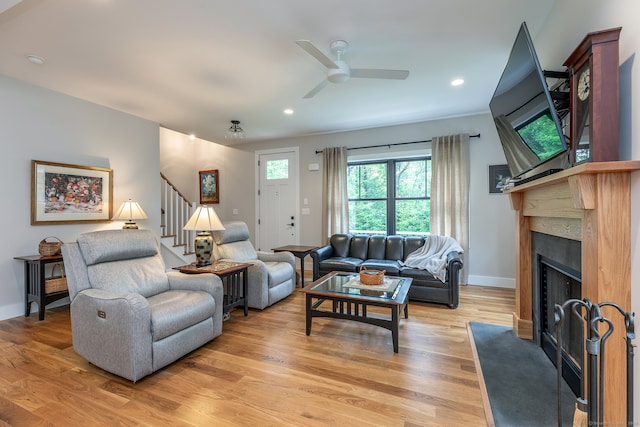 living room featuring light hardwood / wood-style floors, a premium fireplace, and ceiling fan