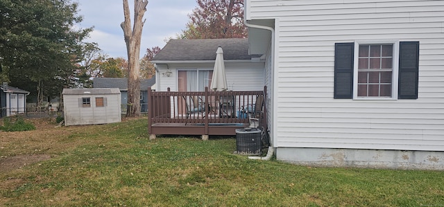 rear view of property featuring central AC, a wooden deck, a shed, and a lawn