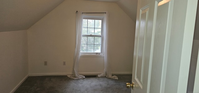 bonus room featuring dark carpet, vaulted ceiling, and a healthy amount of sunlight