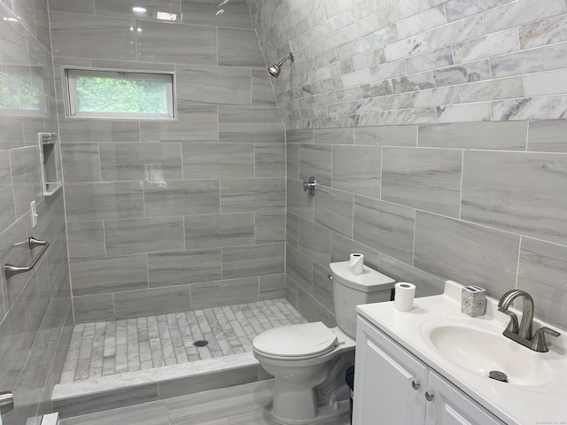 bathroom featuring vanity, tile walls, a tile shower, and toilet