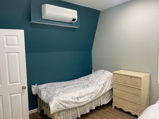 bedroom with a wall mounted AC and dark wood-type flooring