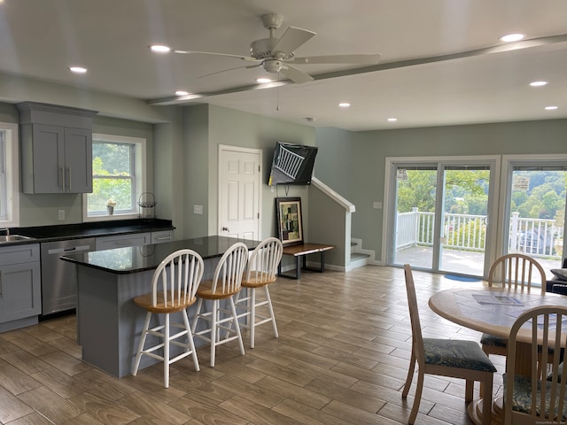 kitchen with ceiling fan, gray cabinetry, wood-type flooring, and stainless steel dishwasher