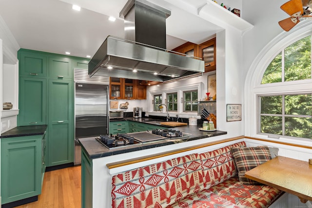 kitchen featuring breakfast area, black gas cooktop, island exhaust hood, and green cabinets