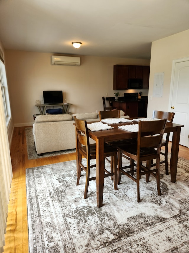 dining space featuring a wall unit AC and light hardwood / wood-style floors