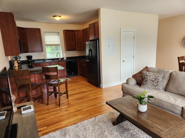 kitchen featuring black appliances, light hardwood / wood-style flooring, sink, and electric panel