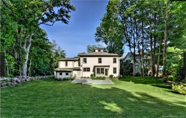 back of house featuring a lawn and a patio