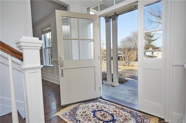 foyer entrance featuring decorative columns and dark hardwood / wood-style flooring