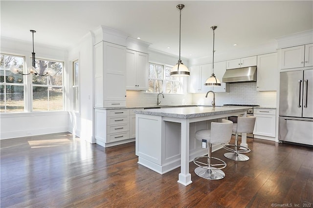 kitchen featuring appliances with stainless steel finishes, dark wood-type flooring, tasteful backsplash, and an island with sink