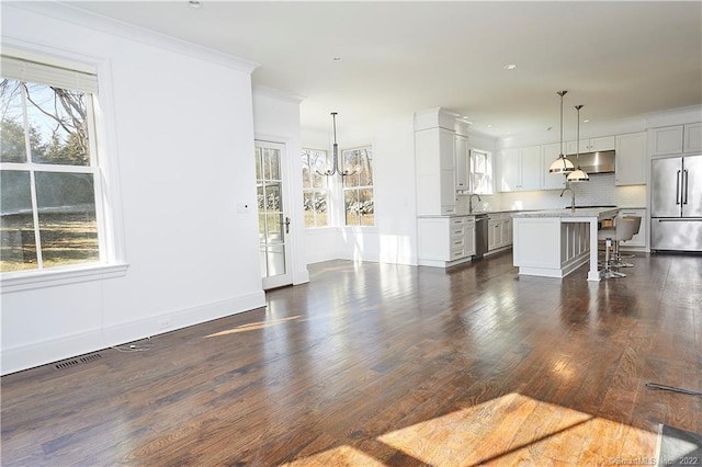 unfurnished living room with sink, a notable chandelier, ornamental molding, and dark hardwood / wood-style flooring