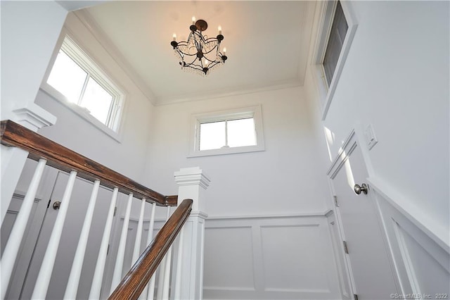 staircase featuring crown molding, a chandelier, and a towering ceiling