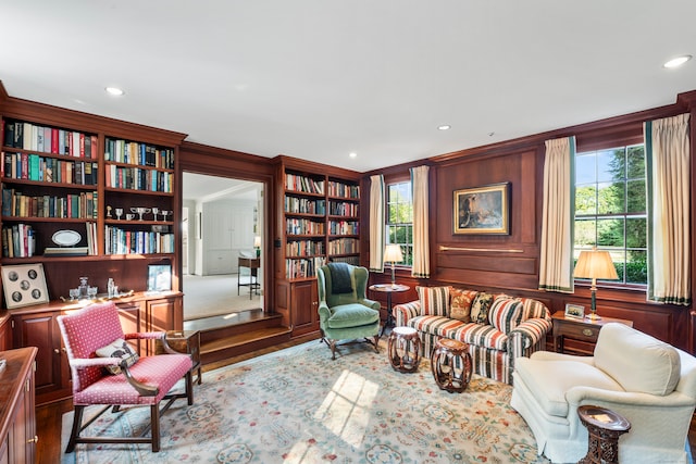 living area featuring wooden walls, ornamental molding, and hardwood / wood-style floors