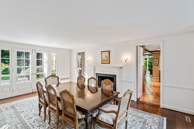 dining room with a brick fireplace, crown molding, dark wood-type flooring, and a wealth of natural light