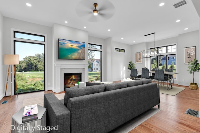 living room with a high end fireplace, a healthy amount of sunlight, and light hardwood / wood-style floors