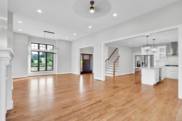 unfurnished living room featuring ceiling fan with notable chandelier, beverage cooler, and light hardwood / wood-style floors