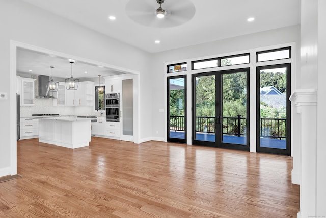 unfurnished living room featuring french doors, ceiling fan, and light hardwood / wood-style flooring