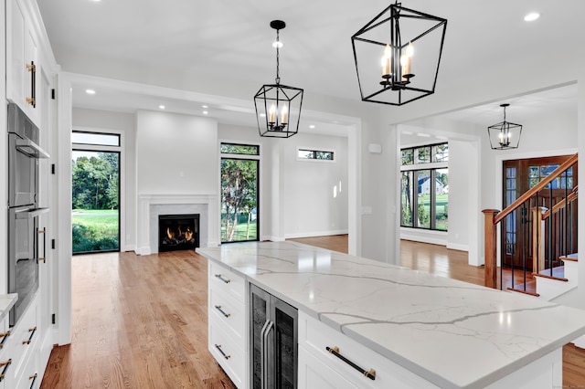 kitchen featuring white cabinets, light wood-type flooring, and beverage cooler