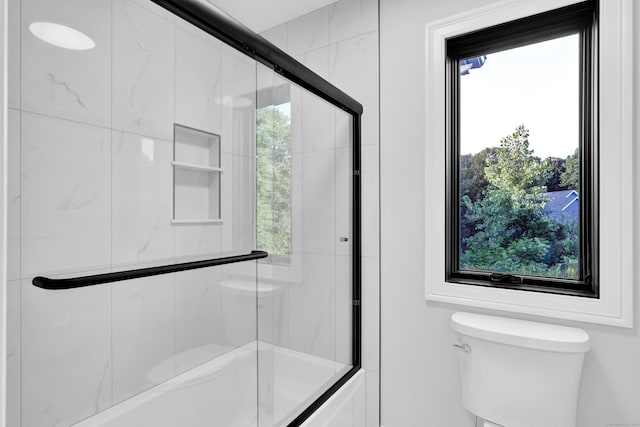 bathroom featuring toilet and combined bath / shower with glass door