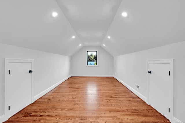 bonus room with lofted ceiling and light wood-type flooring