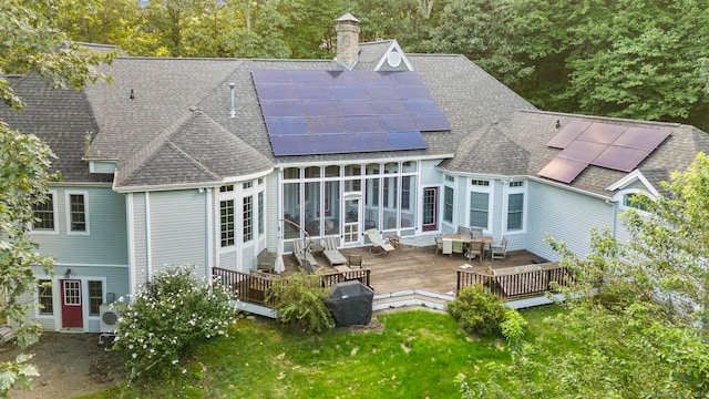 back of property featuring solar panels and a deck