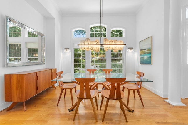 dining area featuring decorative columns, light hardwood / wood-style flooring, and crown molding