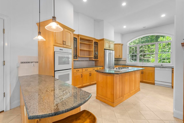 kitchen featuring a kitchen island, kitchen peninsula, a breakfast bar, pendant lighting, and white appliances