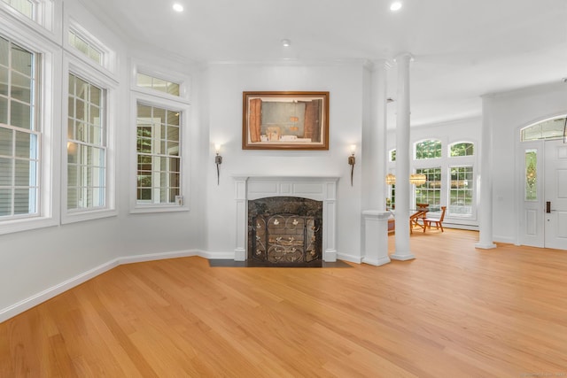 unfurnished living room featuring light hardwood / wood-style floors, decorative columns, and ornamental molding