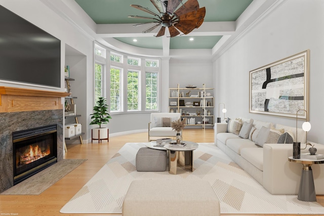 living room featuring a high end fireplace, light wood-type flooring, and ceiling fan