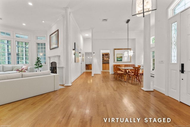 entryway with an inviting chandelier, crown molding, light hardwood / wood-style floors, and a high ceiling