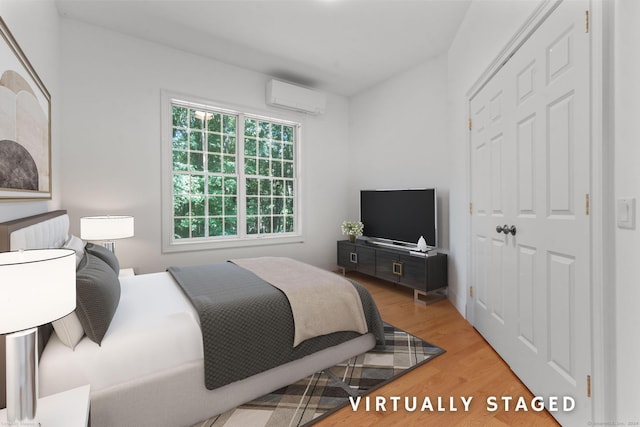 bedroom featuring a wall mounted air conditioner and light hardwood / wood-style flooring