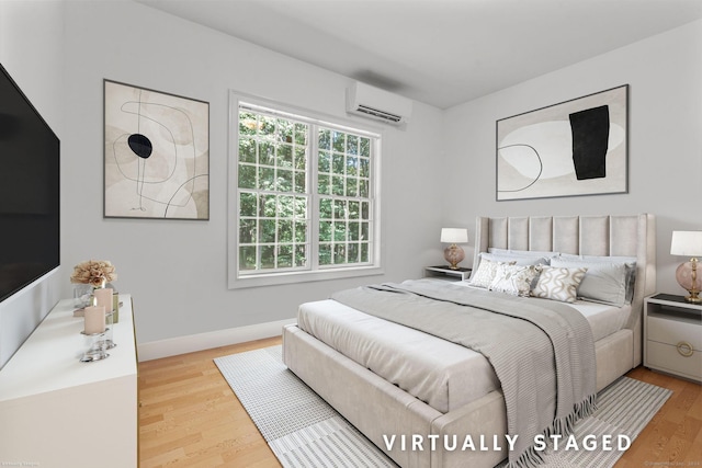 bedroom featuring a wall mounted air conditioner and light hardwood / wood-style floors