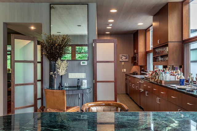 kitchen featuring dark stone countertops, light tile patterned floors, and sink