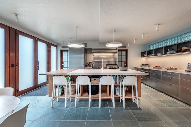 kitchen with pendant lighting, a breakfast bar, french doors, a large island, and stainless steel refrigerator