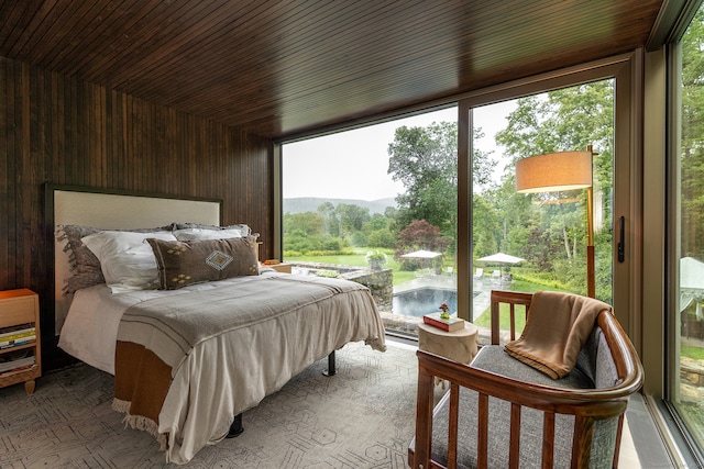 bedroom with a water view, multiple windows, and wood ceiling