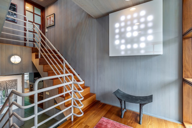 stairway with hardwood / wood-style flooring and wooden walls