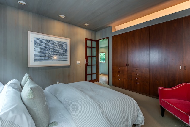 bedroom with wood walls and light colored carpet