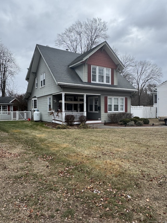 rear view of house featuring covered porch and a lawn