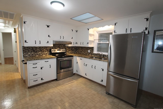 kitchen with appliances with stainless steel finishes, tasteful backsplash, sink, dark stone countertops, and white cabinets