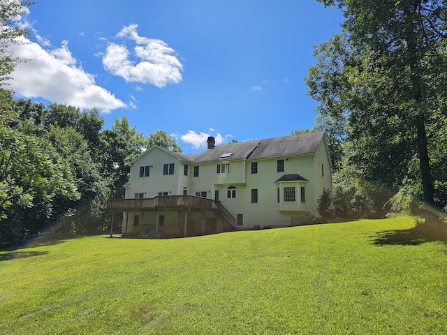 back of property with a yard and a deck