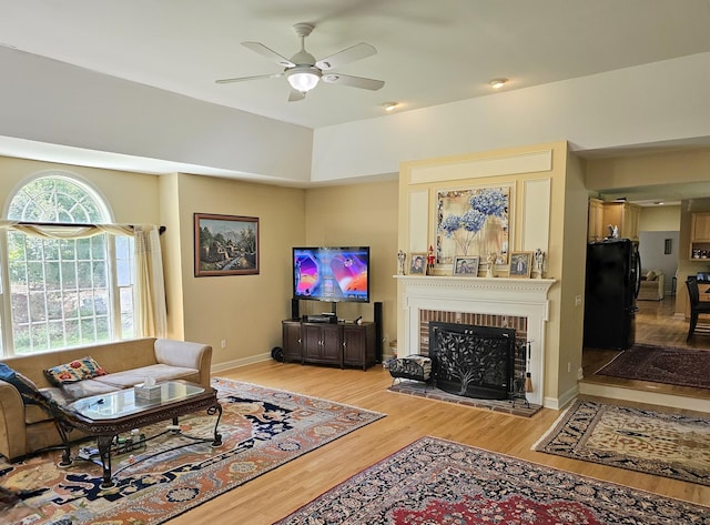 living room with ceiling fan, light hardwood / wood-style floors, and a brick fireplace