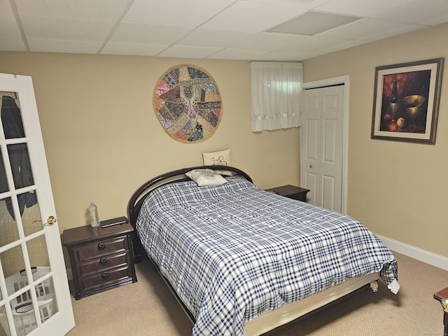 bedroom with light colored carpet, a paneled ceiling, and a closet