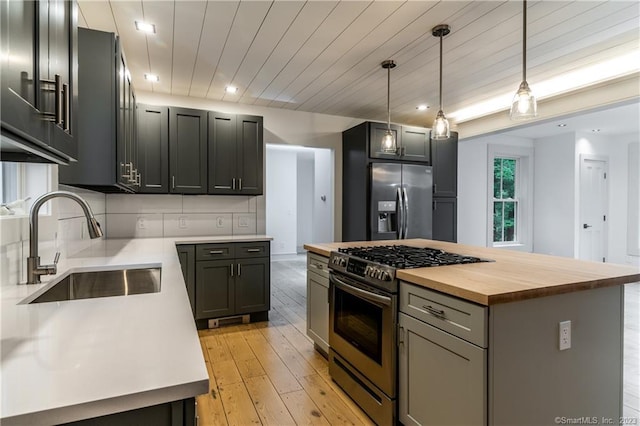 kitchen with hanging light fixtures, appliances with stainless steel finishes, a kitchen island, tasteful backsplash, and light hardwood / wood-style floors