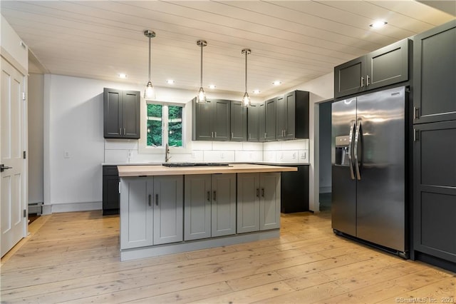 kitchen featuring decorative backsplash, a kitchen island, light hardwood / wood-style floors, and stainless steel fridge