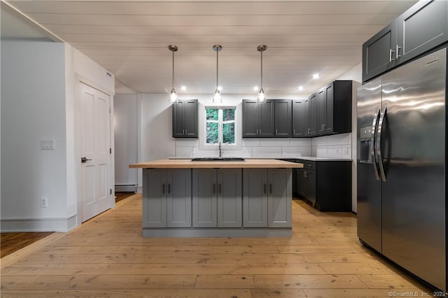 kitchen with stainless steel fridge with ice dispenser, light hardwood / wood-style floors, a center island, decorative backsplash, and butcher block counters