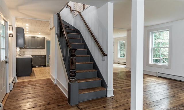 staircase featuring sink, wood-type flooring, and baseboard heating